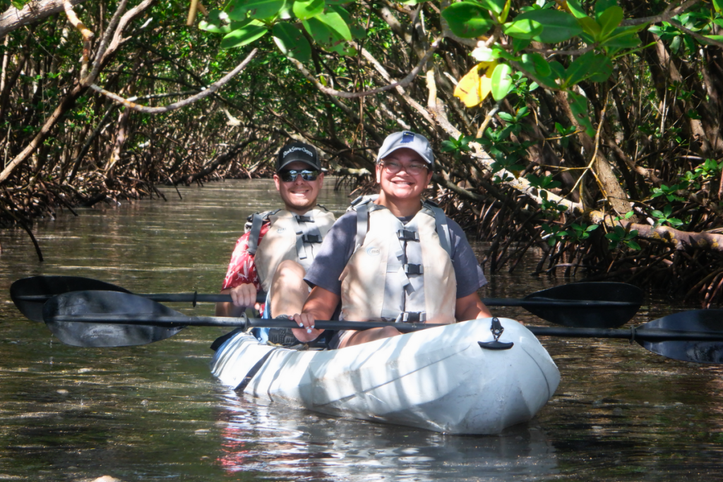 A pair on tandem kayak in mangrove tunnel.